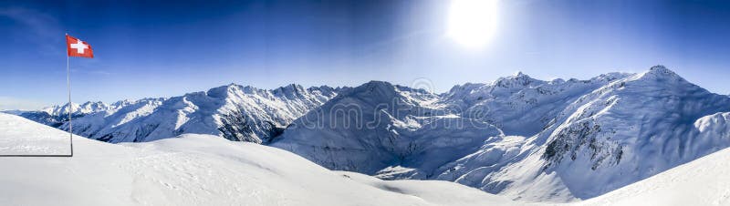 Swiss alps mountain range in winter with blue sky and switzerland national flag