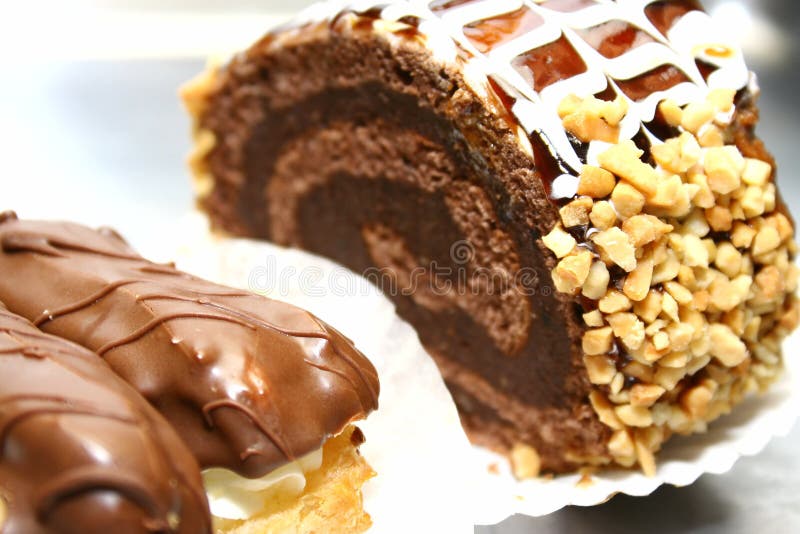 Swiss roll with nuts and chocolate and two eclairs stock image