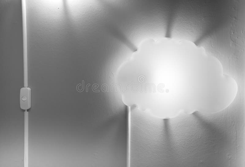 Switch turned on next to illuminated white cloud-shaped lamp attached on grey wall with scattered dark shadow royalty free stock photos Switch turned on next to illuminated white cloud-shaped lamp attached on grey wall with scattered dark shadow royalty free stock photos