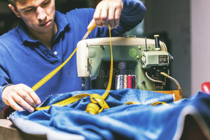 Sy grov bomullstvilljeans med symaskinen Reparationsjeans vid symaskinen Förändringsjeans som fållar ett par jeans som är handgjo arkivfoto Sy grov bomullstvilljeans med symaskinen Reparationsjeans vid symaskinen Förändringsjeans som fållar ett par jeans som är handgjo arkivfoto