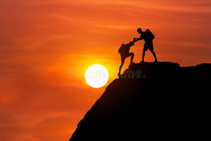 Sylwetka alpinista daje pomocnej dłoni jego przyjaciela wspinać się wysoką falezy górę wpólnie
