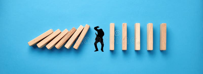 Sylwetka mężczyzny w panice próbuje się chronić przed upadkiem drewnianych domino na niebieskim tle. kryzysu gospodarczego i