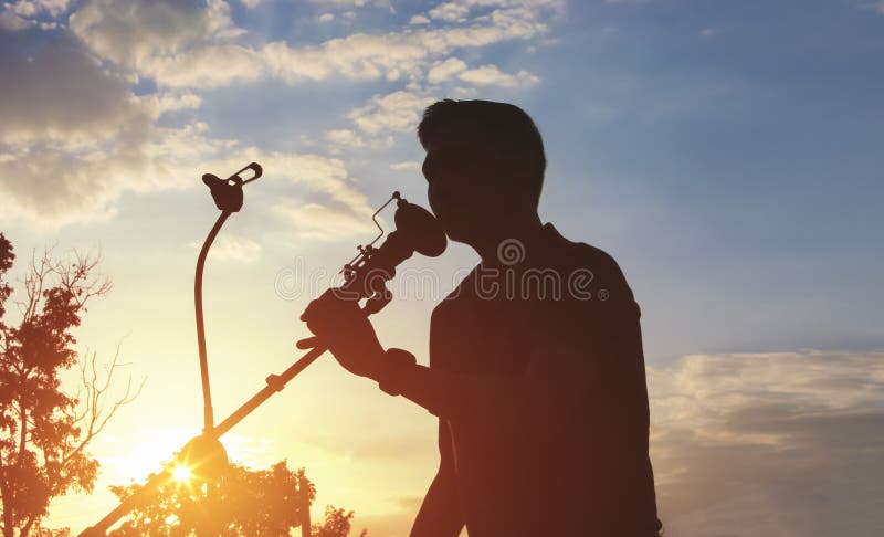 Sylwetka Singera trzymającego podstawkę mikrofonu i występującego na zewnątrz zdjęcie royalty free
