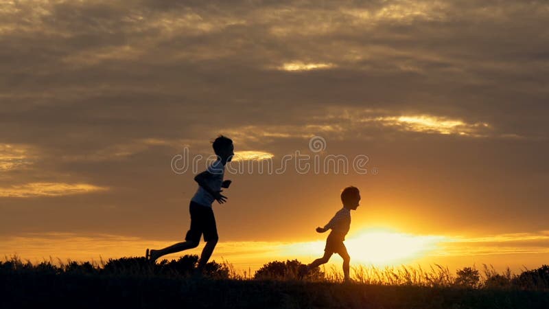 Sylwetki działający dzieci w polu przy zmierzchem