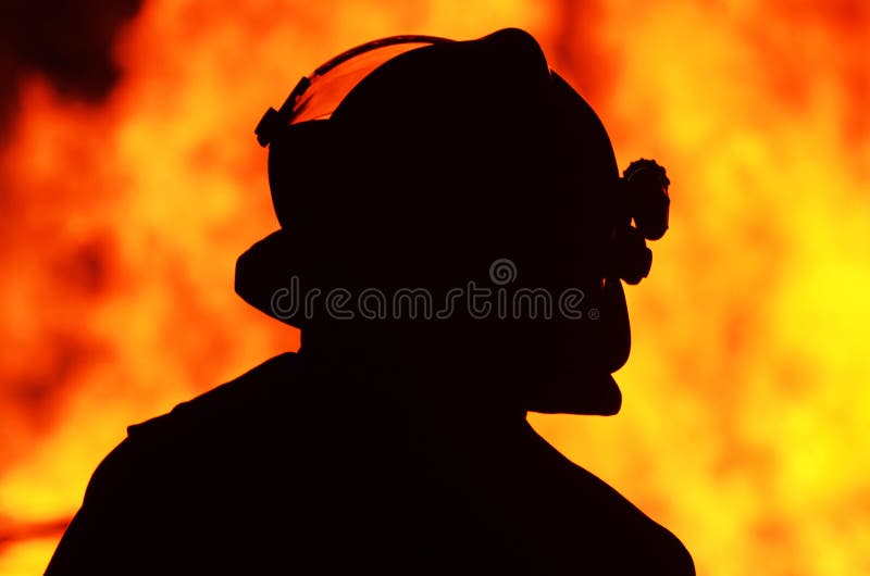 A black silhouette image of a single brave rescue firefighter standing in front and watching a bushfire blaze. He is cautious and keeping control of the blazing hot bushfire so that it does not spread and cause danger to surrounding homes and buildings. Photograph taken in small Queensland country town of Kalbar situated on the Scenic Rim, Australia. A black silhouette image of a single brave rescue firefighter standing in front and watching a bushfire blaze. He is cautious and keeping control of the blazing hot bushfire so that it does not spread and cause danger to surrounding homes and buildings. Photograph taken in small Queensland country town of Kalbar situated on the Scenic Rim, Australia.