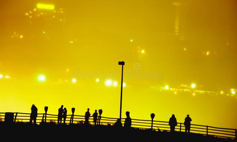 Sylwetki od ludzie przy Niagara spadkami obserwatorskimi przy nocą od amerykanin strony z kanadyjczyk stroną iluminującą przez mg