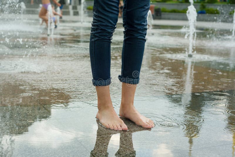 Symbol des Sommerbrunnens, Kühle Beine des Mädchens in der nassen Kleidung im Brunnen lizenzfreie stockbilder Symbol des Sommerbrunnens, Kühle Beine des Mädchens in der nassen Kleidung im Brunnen lizenzfreie stockbilder