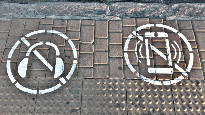 Symbol des Verbots, zum des Handys und des Hörens Musik mit Kopfhörern zu betrachten, bei der Kreuzung der Straße lizenzfreies stockfoto Symbol des Verbots, zum des Handys und des Hörens Musik mit Kopfhörern zu betrachten, bei der Kreuzung der Straße lizenzfreies stockfoto