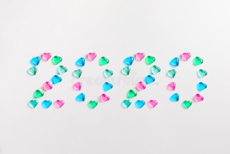 Happy New Year 2020. Symbol from number 2020 made of pastel colored decorative glass hearts laying on white paper background. Copy Space For Text. MInimal flat lay holiday concept, greeting, card, figure, festive, creative, bright, design, calendar, congratulation, colorful, shiny, poster, event, postcard, pink, above, abstract, merry, view, decoration, tree, winter, top, december, xmas, love, green, blue, modern, unicorn, style