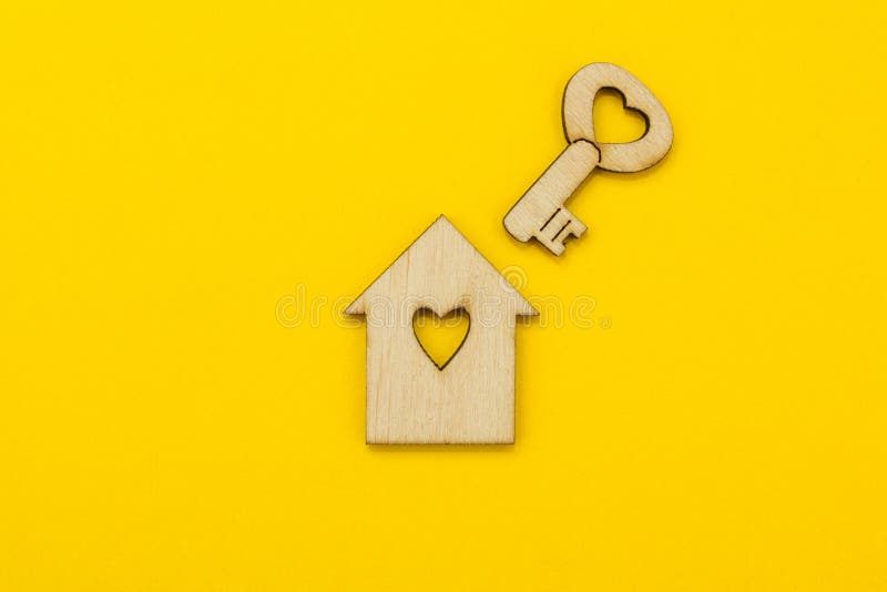 Symbole d'une petite maison et une clé avec un coeur sur un fond jaune photographie stock Symbole d'une petite maison et une clé avec un coeur sur un fond jaune photographie stock