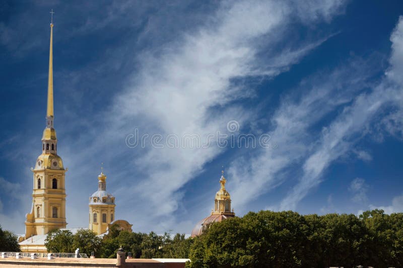 Magnificent view of the buildings of the Peter and Paul Fortress in the center of St. Petersburg, Russia, towers of an ancient Orthodox cathedral with a huge gilded spire, domes and crosses, sky and clouds, European architecture, green plants, cityscape, summer. Magnificent view of the buildings of the Peter and Paul Fortress in the center of St. Petersburg, Russia, towers of an ancient Orthodox cathedral with a huge gilded spire, domes and crosses, sky and clouds, European architecture, green plants, cityscape, summer.