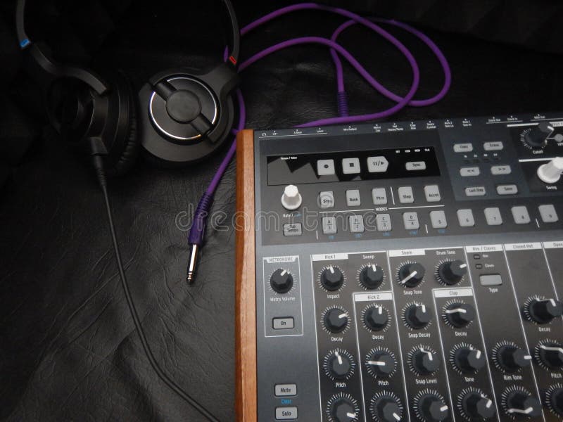 Synthesizer with headphones on black leather background with purple patch cable royalty free stock photo