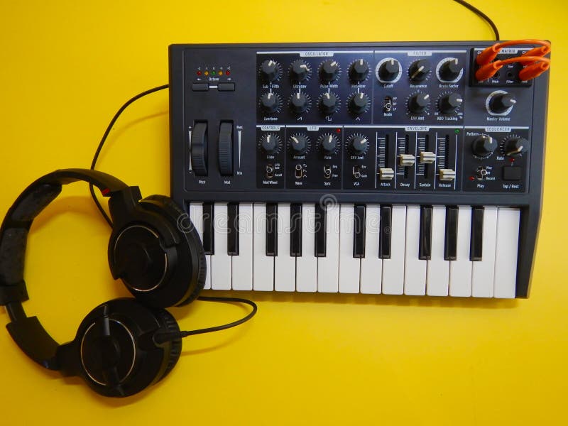 Synthesizer on yellow background with orange patch cables and headphones royalty free stock photo