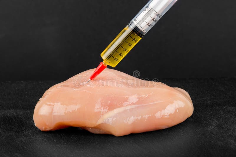 Syringe with liquid being injected to a piece of meat
