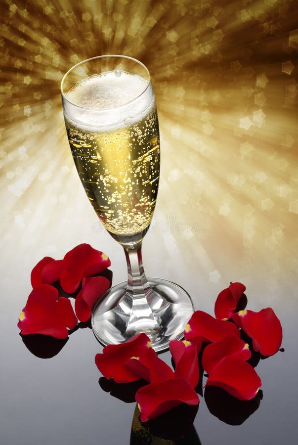 Champagne glass with red rose petals against a glitter background. Champagne glass with red rose petals against a glitter background
