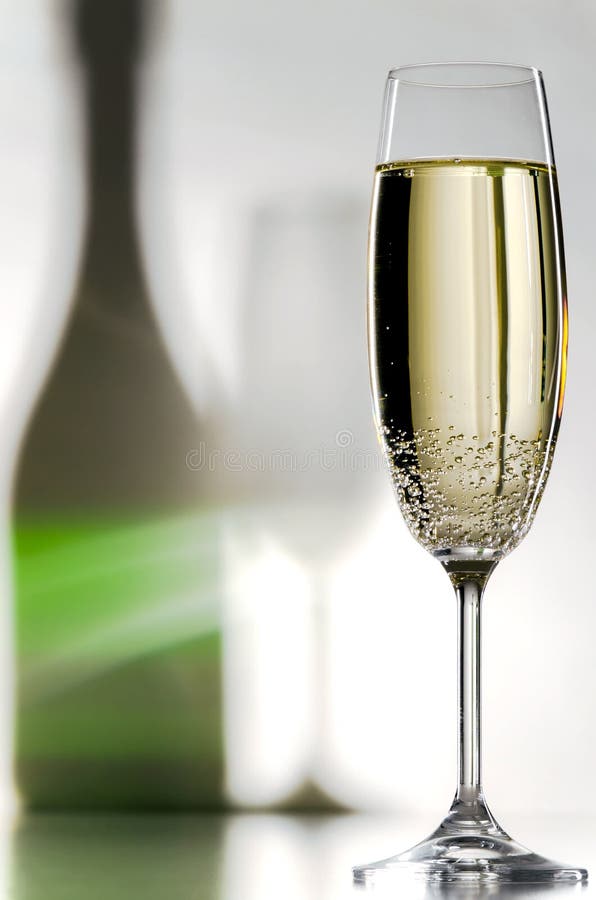 A filled champagne glass with shadows in the background. A filled champagne glass with shadows in the background