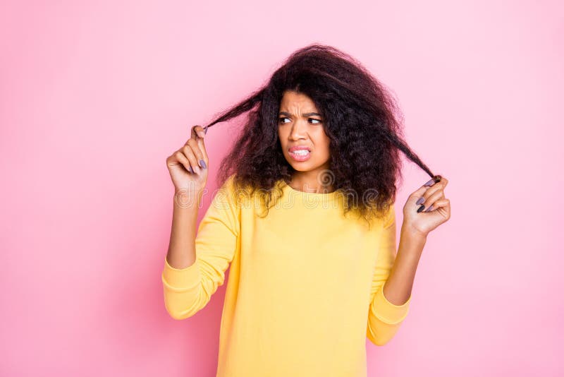 Bad quality shampoo. I dont like it. Portrait of frustrated black girl look her hair dislike new, anti dander dandruff shampoo unsatisfied salon treatment wear yellow sweater  pink color background. Bad quality shampoo. I dont like it. Portrait of frustrated black girl look her hair dislike new, anti dander dandruff shampoo unsatisfied salon treatment wear yellow sweater  pink color background