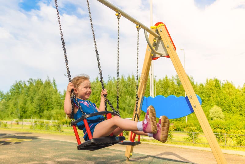 Szcz??liwa ma?e dziecko dziewczyna ?mia si? i hu?ta si? na hu?tawce w miasto parku w lecie zdjęcie royalty free Szcz??liwa ma?e dziecko dziewczyna ?mia si? i hu?ta si? na hu?tawce w miasto parku w lecie zdjęcie royalty free
