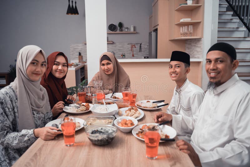 Group of happy muslim having dinner at home looking to camera during ramadan celebration, break fasting. Group of happy muslim having dinner at home looking to camera during ramadan celebration, break fasting