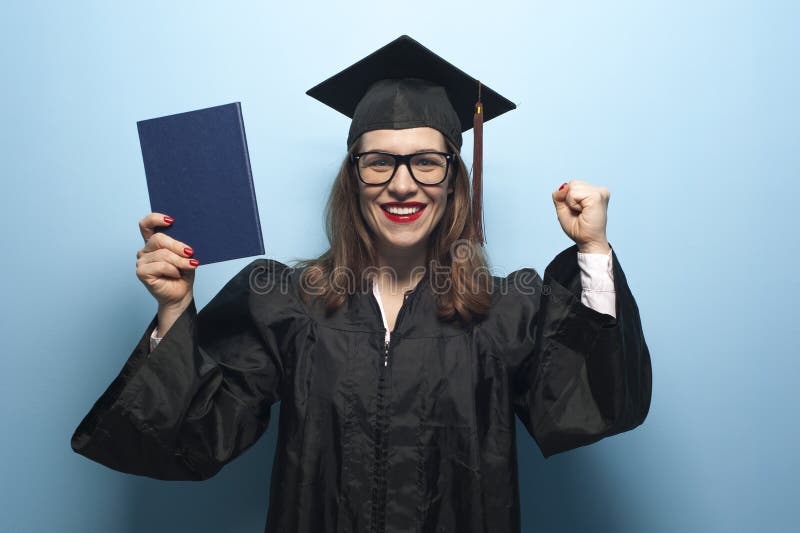 Happy smiling graduate female student with diploma. Happy smiling graduate female student with stubble in eyeglasses wearing black mantle and mortarboard holding up diploma crying out
