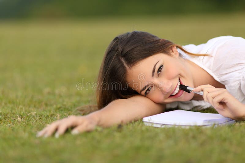 Szczery szczęśliwy kobiety lying on the beach na trawy writing