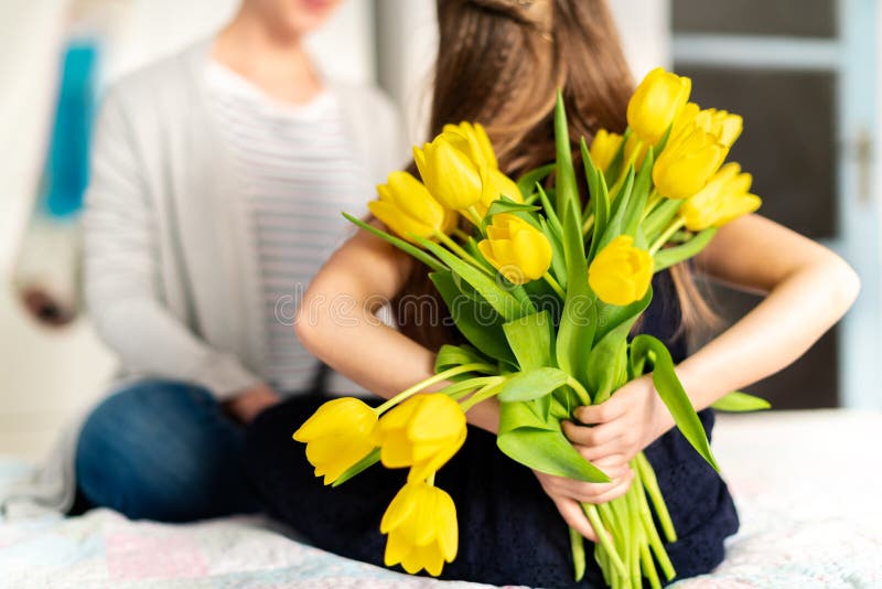 Szczęśliwy matka urodziny lub dnia tło Unrecognizable młoda dziewczyna zaskakuje jej mamy z bukietem żółci tulipany obraz royalty free Szczęśliwy matka urodziny lub dnia tło Unrecognizable młoda dziewczyna zaskakuje jej mamy z bukietem żółci tulipany obraz royalty free