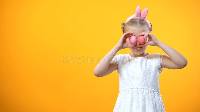 Szczęśliwy małej dziewczynki mienie barwił Wielkanocnych jajka w frontowych oczach, ono uśmiecha się na kamerze zdjęcia royalty free Szczęśliwy małej dziewczynki mienie barwił Wielkanocnych jajka w frontowych oczach, ono uśmiecha się na kamerze zdjęcia royalty free