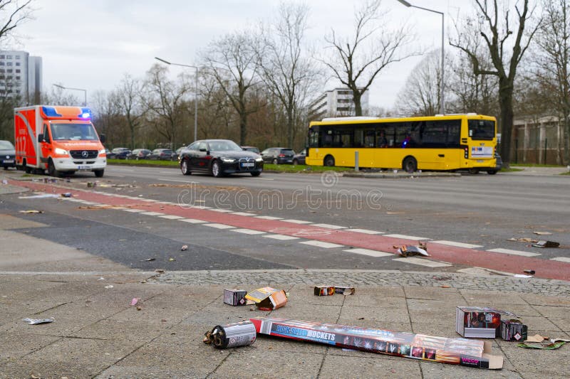 Berlin, Germany - January 1, 2024: Street scene with fireworks debris in the foreground and a fire department ambulance in the background. Berlin, Germany - January 1, 2024: Street scene with fireworks debris in the foreground and a fire department ambulance in the background