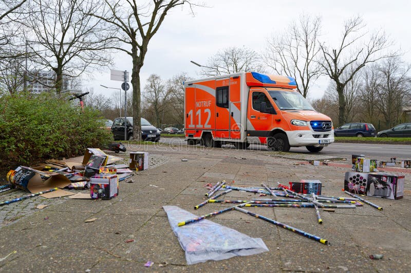 Berlin, Germany - January 1, 2024: Street scene with fireworks debris in the foreground and a fire department ambulance in the background. Berlin, Germany - January 1, 2024: Street scene with fireworks debris in the foreground and a fire department ambulance in the background