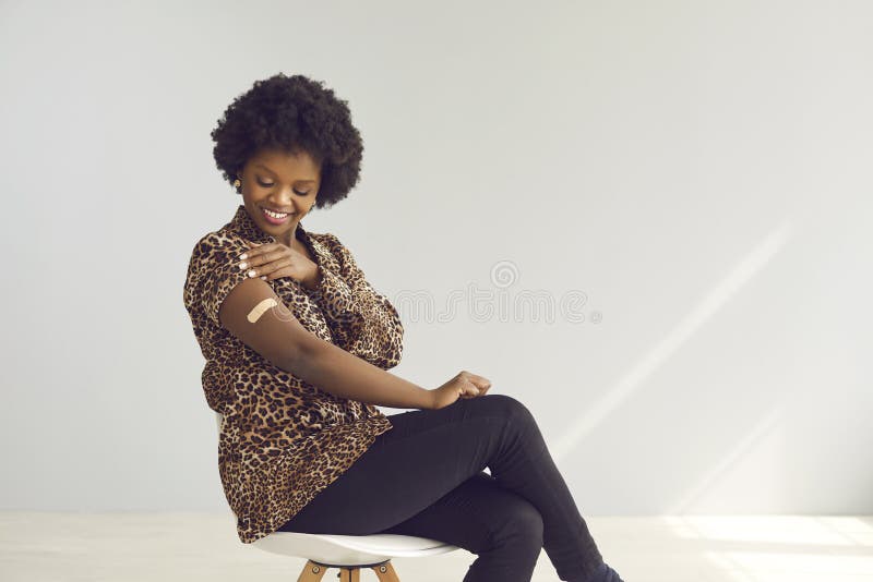 Szczęśliwa afrykańska kobieta pokazuje ramię po udaniu się na krzesło na tle studia kopiującego
