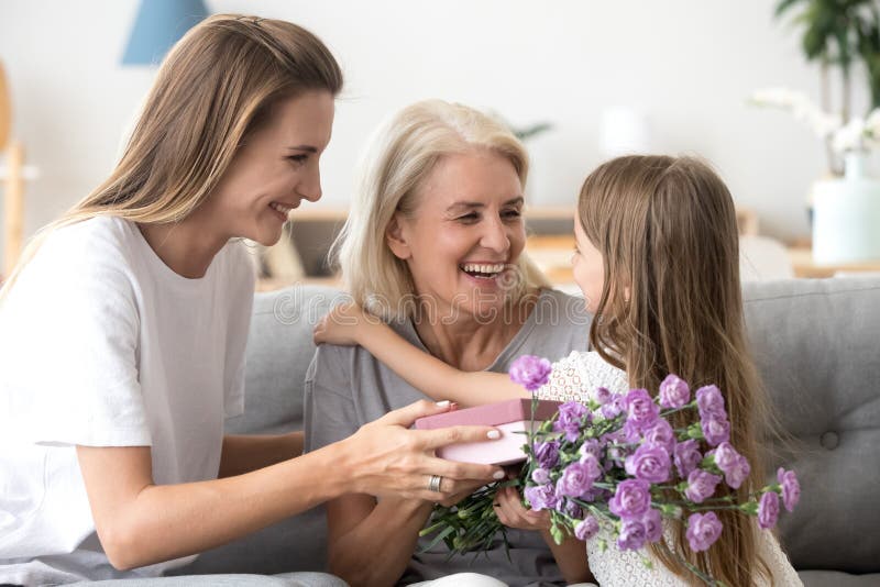 Szczęśliwa babcia dziękuje wnuka i r córki dla kwiatów fotografia stock Szczęśliwa babcia dziękuje wnuka i r córki dla kwiatów fotografia stock