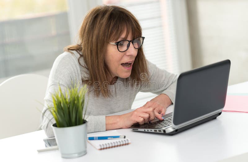 Szczęśliwa dojrzała kobieta ma dobrą niespodziankę na laptopie zdjęcia stock Szczęśliwa dojrzała kobieta ma dobrą niespodziankę na laptopie zdjęcia stock
