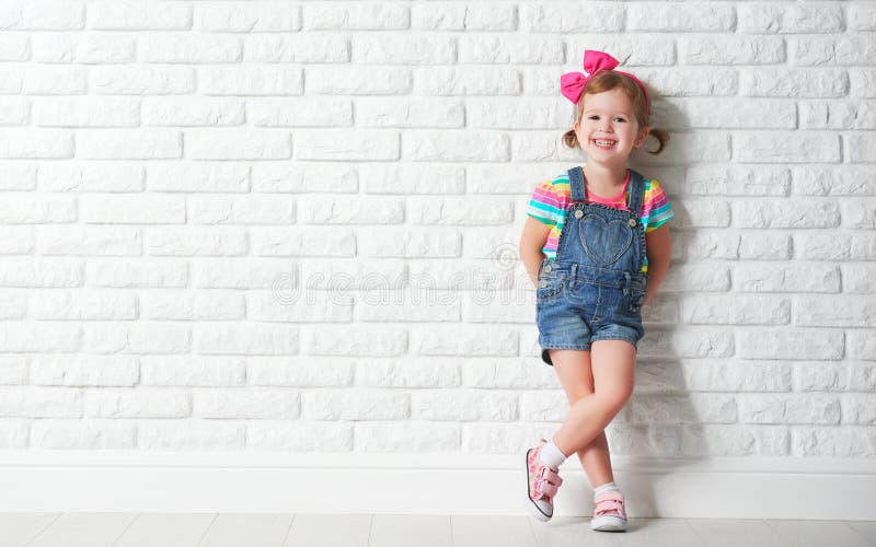 Szczęśliwa dziecko mała dziewczynka śmia się przy pustym ściana z cegieł