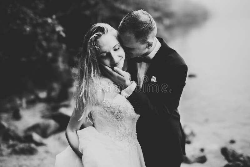 Szczęśliwa i romantyczna scena właśnie zamężna młoda ślub para pozuje na pięknej plaży fotografia stock Szczęśliwa i romantyczna scena właśnie zamężna młoda ślub para pozuje na pięknej plaży fotografia stock