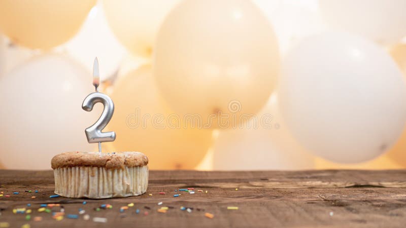 Happy birthday card with candle number 2 in a cupcake against the background of balloons. Copy space happy birthday for two years old. Happy birthday card with candle number 2 in a cupcake against the background of balloons. Copy space happy birthday for two years old.