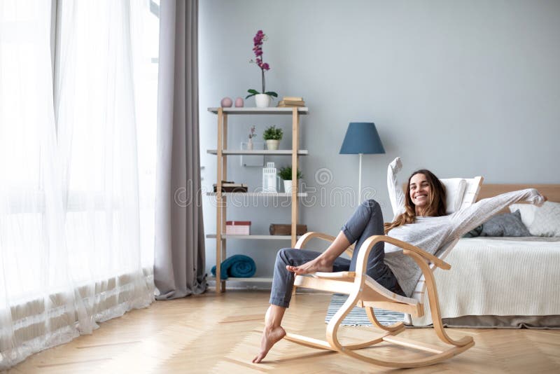 Happy woman resting comfortably sitting on modern chair in the living room at home. Lifestyle. Happy woman resting comfortably sitting on modern chair in the living room at home. Lifestyle