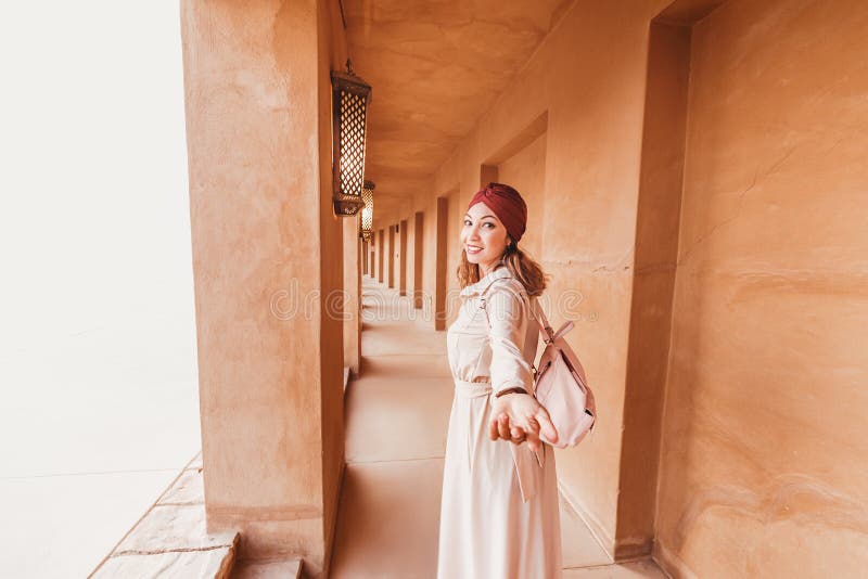 Szczęśliwa kobieta podróżująca ubrana w sukienkę i turban idąca ulicami starego miasteczka arabskiego lub wioski w środku obraz stock