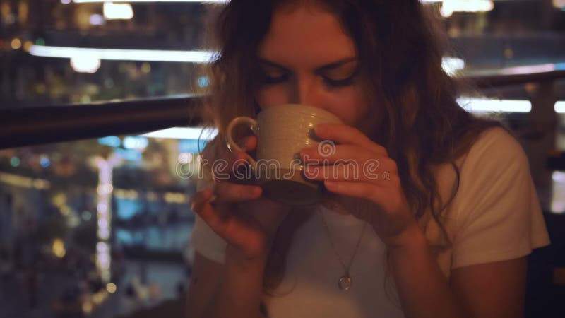Szczęśliwa kobieta turystka bierze filiżankę w ręce pije smaczne kawy. Blondynka siedzi w kafejce w miejscu publicznym. zdjęcie wideo