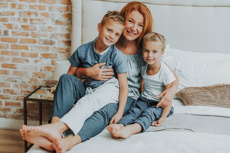 Szczęśliwa mama i dwa dzieciaka relaksuje w łóżku obrazy stock Szczęśliwa mama i dwa dzieciaka relaksuje w łóżku obrazy stock