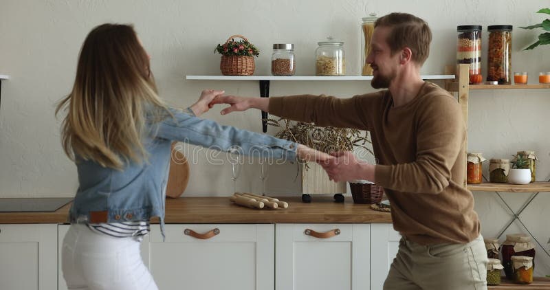 Szczęśliwa małżeńska para trzymająca ręce tańczące razem w kuchni