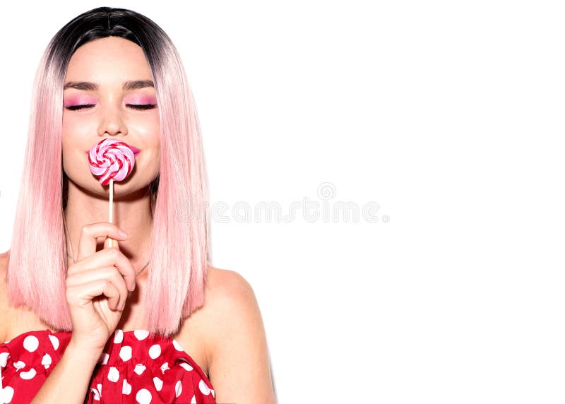 Szczęśliwa modelka jedząca lizaka. piękna glamour młoda kobieta z modnym różowym fryzurą i pięknym makijażem