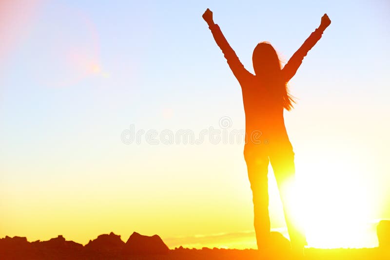 Happy celebrating winning success woman at sunset or sunrise standing elated with arms raised up above her head in celebration of having reached mountain top summit goal during hiking travel trek. Happy celebrating winning success woman at sunset or sunrise standing elated with arms raised up above her head in celebration of having reached mountain top summit goal during hiking travel trek.