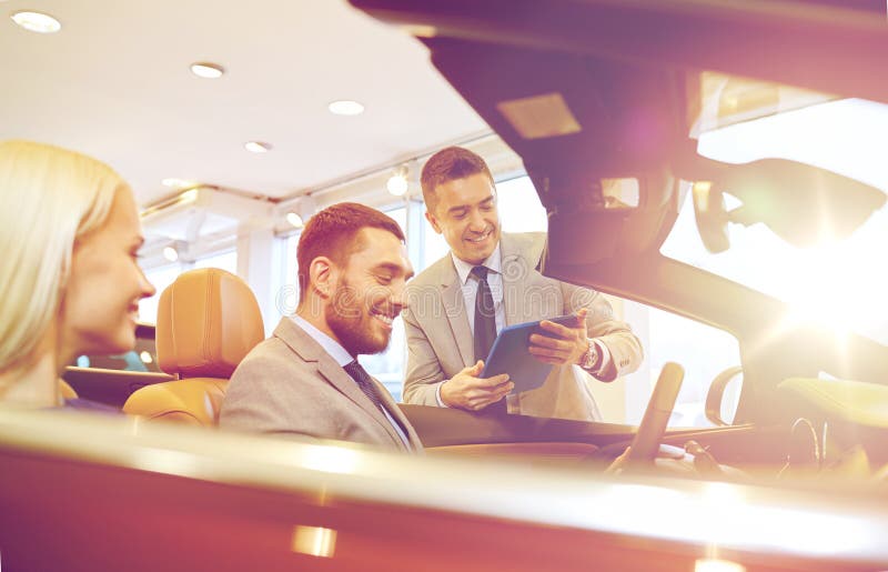 Szczęśliwa para z samochodowym handlowem w auto przedstawieniu lub salonie obrazy royalty free Szczęśliwa para z samochodowym handlowem w auto przedstawieniu lub salonie obrazy royalty free