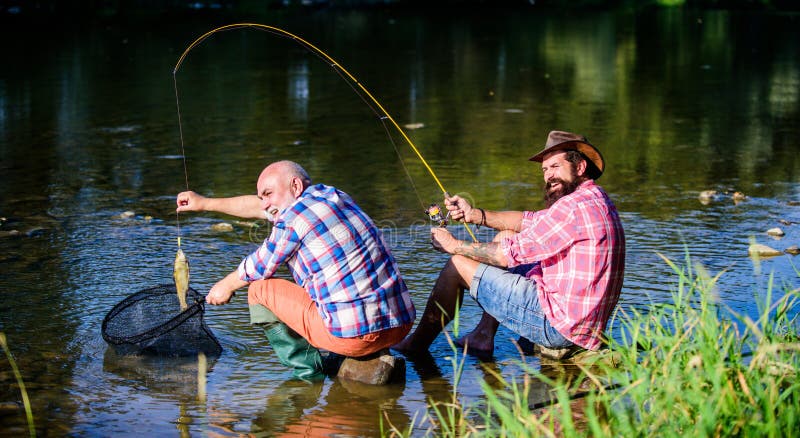 Happy fishermen friendship. Two male friends fishing together. big game fishing. relax on nature. fly fish hobby of men. retired father and mature bearded son. Learning from the professional. Happy fishermen friendship. Two male friends fishing together. big game fishing. relax on nature. fly fish hobby of men. retired father and mature bearded son. Learning from the professional.