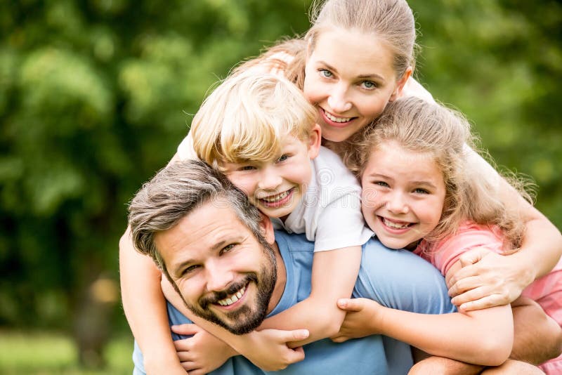 Happy family with two kids hugging together in harmony in garden. Happy family with two kids hugging together in harmony in garden