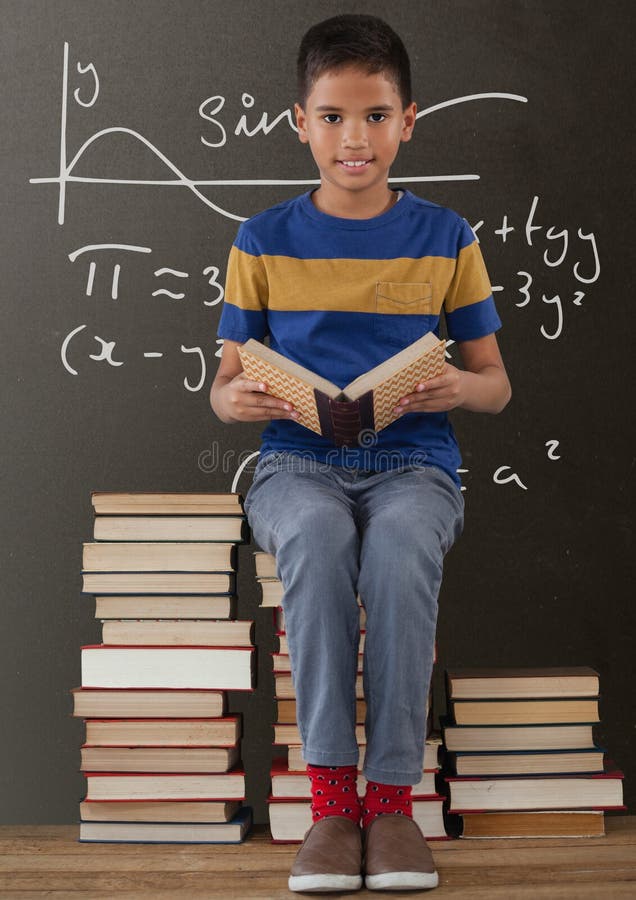 Szczęśliwa studencka chłopiec na stołowym czytaniu przeciw popielatemu blackboard z edukacją i szkół grafika zdjęcia royalty free Szczęśliwa studencka chłopiec na stołowym czytaniu przeciw popielatemu blackboard z edukacją i szkół grafika zdjęcia royalty free