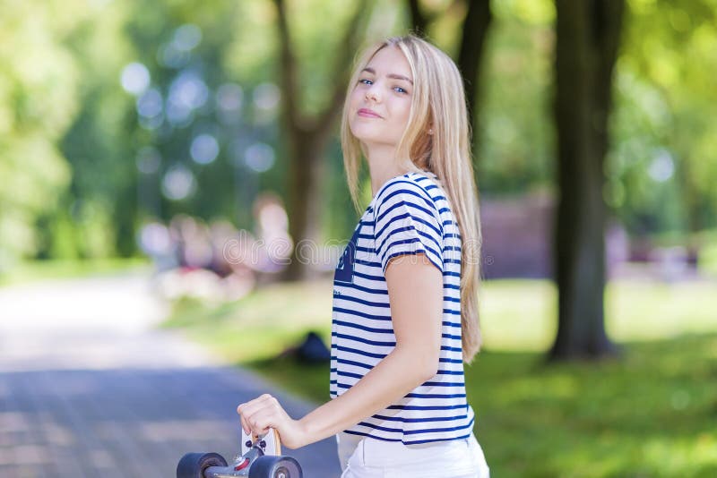 Szczęśliwa Uśmiechnięta Kaukaska nastoletnia dziewczyna Pozuje Z Długi deskorolka Outdoors zdjęcia stock Szczęśliwa Uśmiechnięta Kaukaska nastoletnia dziewczyna Pozuje Z Długi deskorolka Outdoors zdjęcia stock