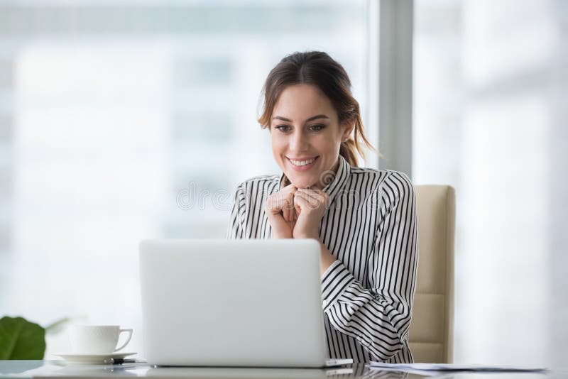 Happy smiling young woman looking at laptop screen. Excited businesswoman received good business offer, business email. Receiving good news concept, got promoted, achieved opportunity concept. Happy smiling young woman looking at laptop screen. Excited businesswoman received good business offer, business email. Receiving good news concept, got promoted, achieved opportunity concept