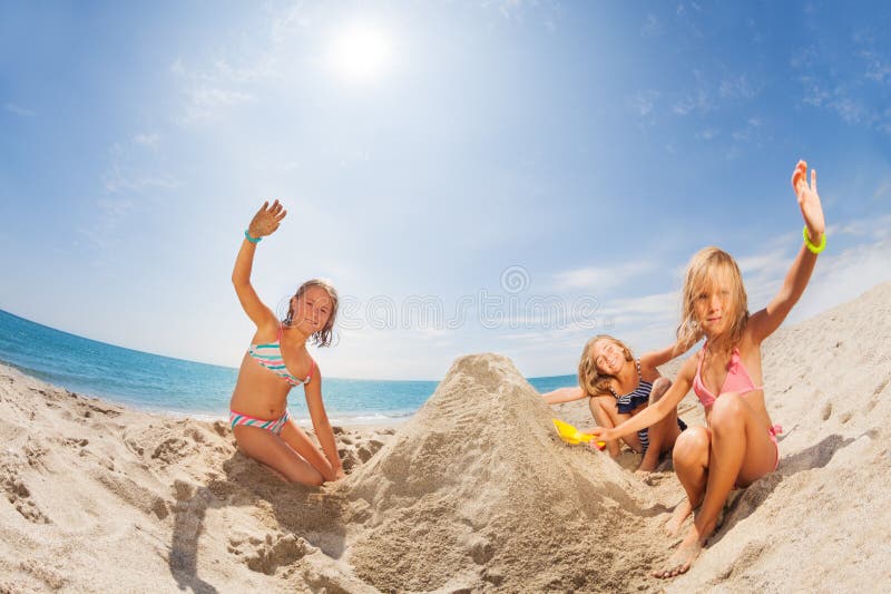 Portrait of three happy girls in swimwear playing sand games at tropical beach at sunny day. Portrait of three happy girls in swimwear playing sand games at tropical beach at sunny day