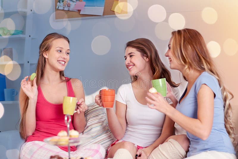 Szczęśliwe młode kobiety pije herbaty z cukierkami w domu